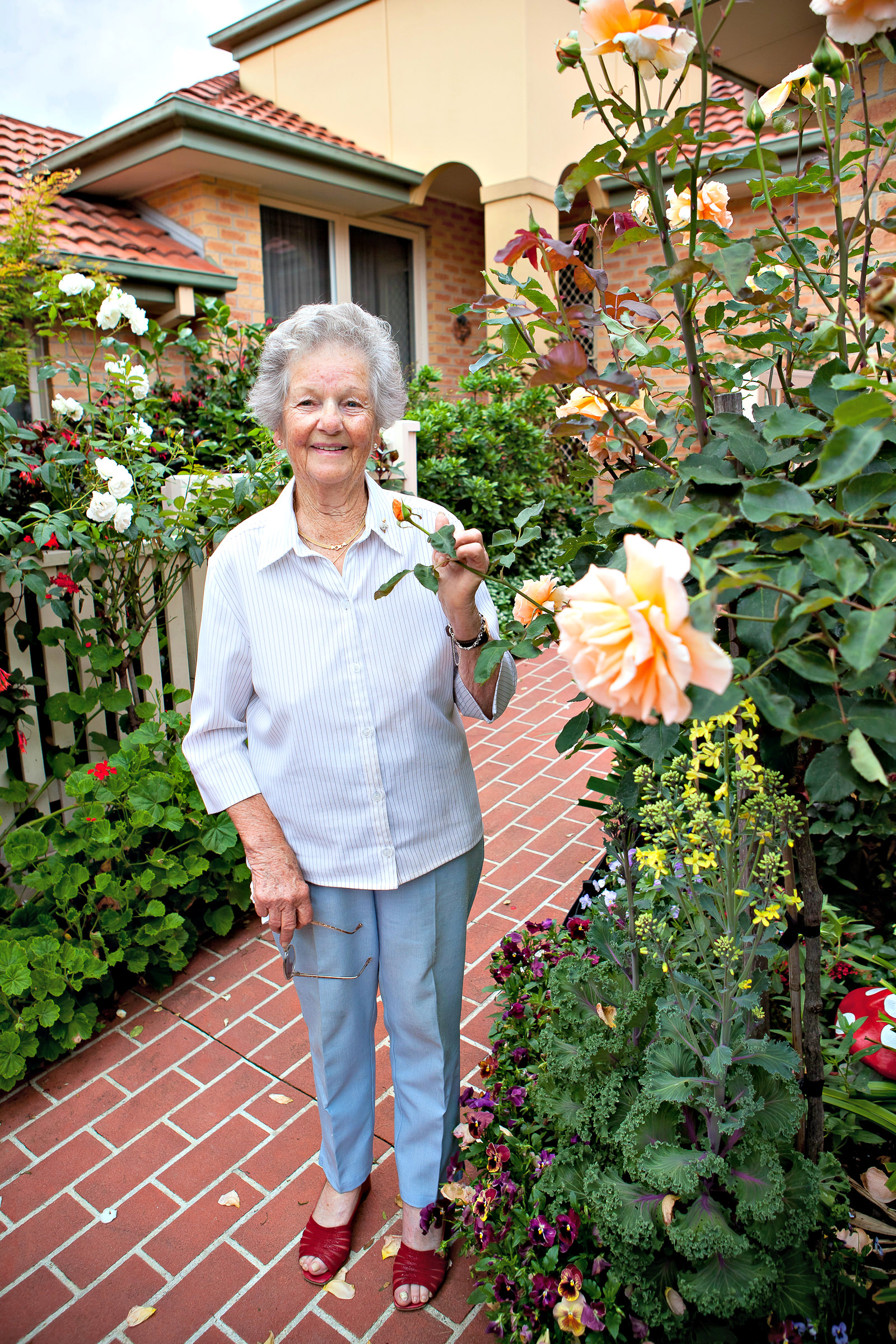 Smelling the roses retired lady in her garden